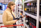 Jeune femme choisissant du vin en supermarché